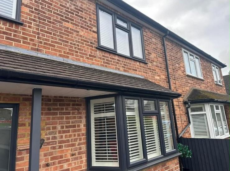 Tiled bay roof and porch canopy with new black fascia and guttering on a brick semi-detached house